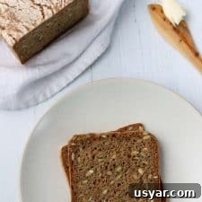 Danish Sourdough Rye Bread Rugbrød Recipe 10 Rye bread slices on a plate next to a loaf of rye bread and a wooden knife with butter
