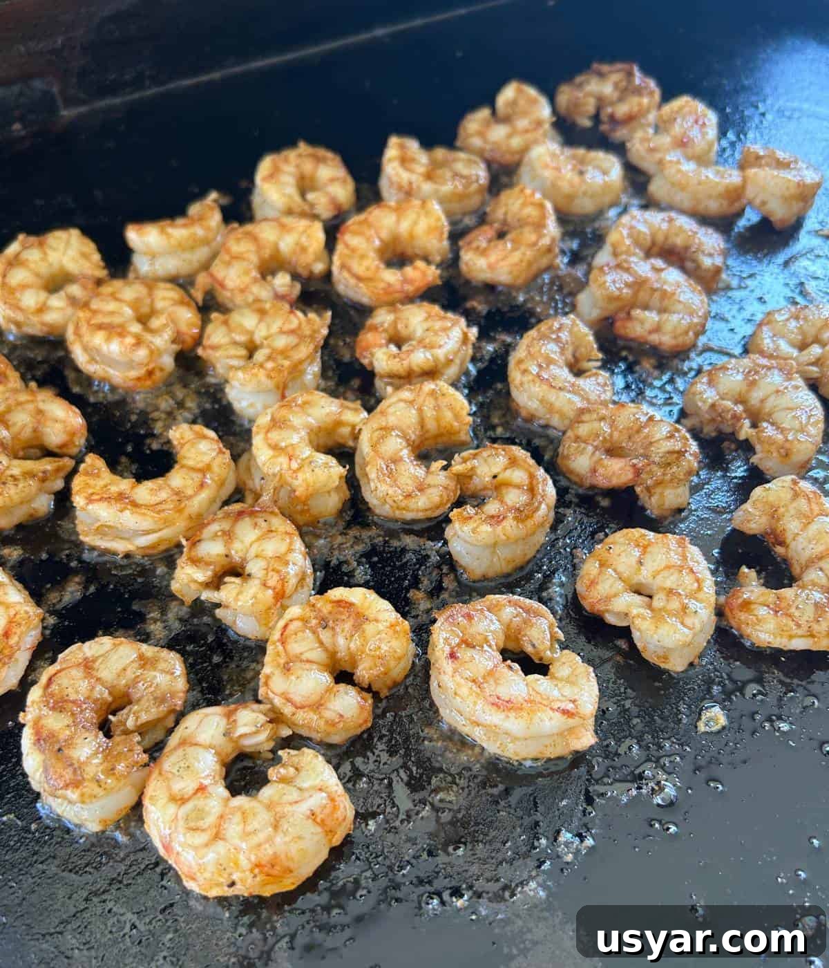 Garlic Butter Shrimp on a Blackstone Griddle 6 Flipped shrimp cooking on blackstone.