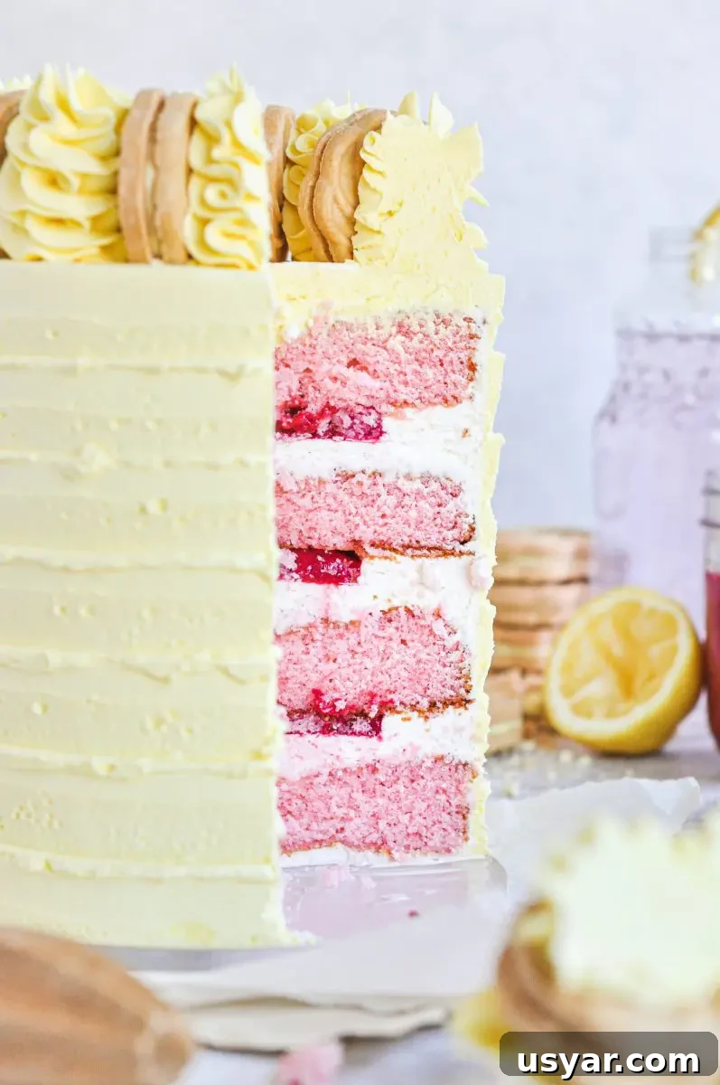 Homemade Pink Lemonade Cake Recipe 6 A yellow cake with a slice taken out of it. You can see the inside cake layers which are pink and have a bright pink raspberry filling in between each layer.