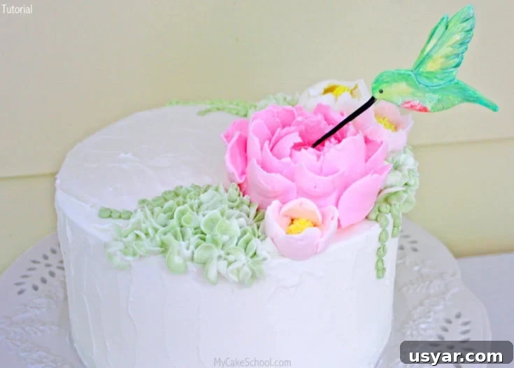 Hummingbird cake topper with fluffy frosting flowers