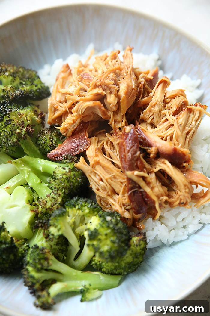 A dinner plate with a serving of honey garlic chicken over white rice along side of a serving of steamed broccoli.