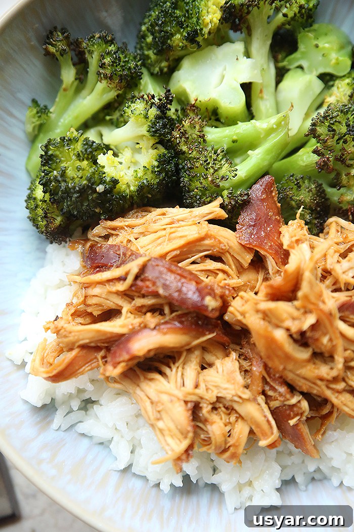 A serving of cooked broccoli and shredded honey garlic chicken over rice on a light blue dinner plate.
