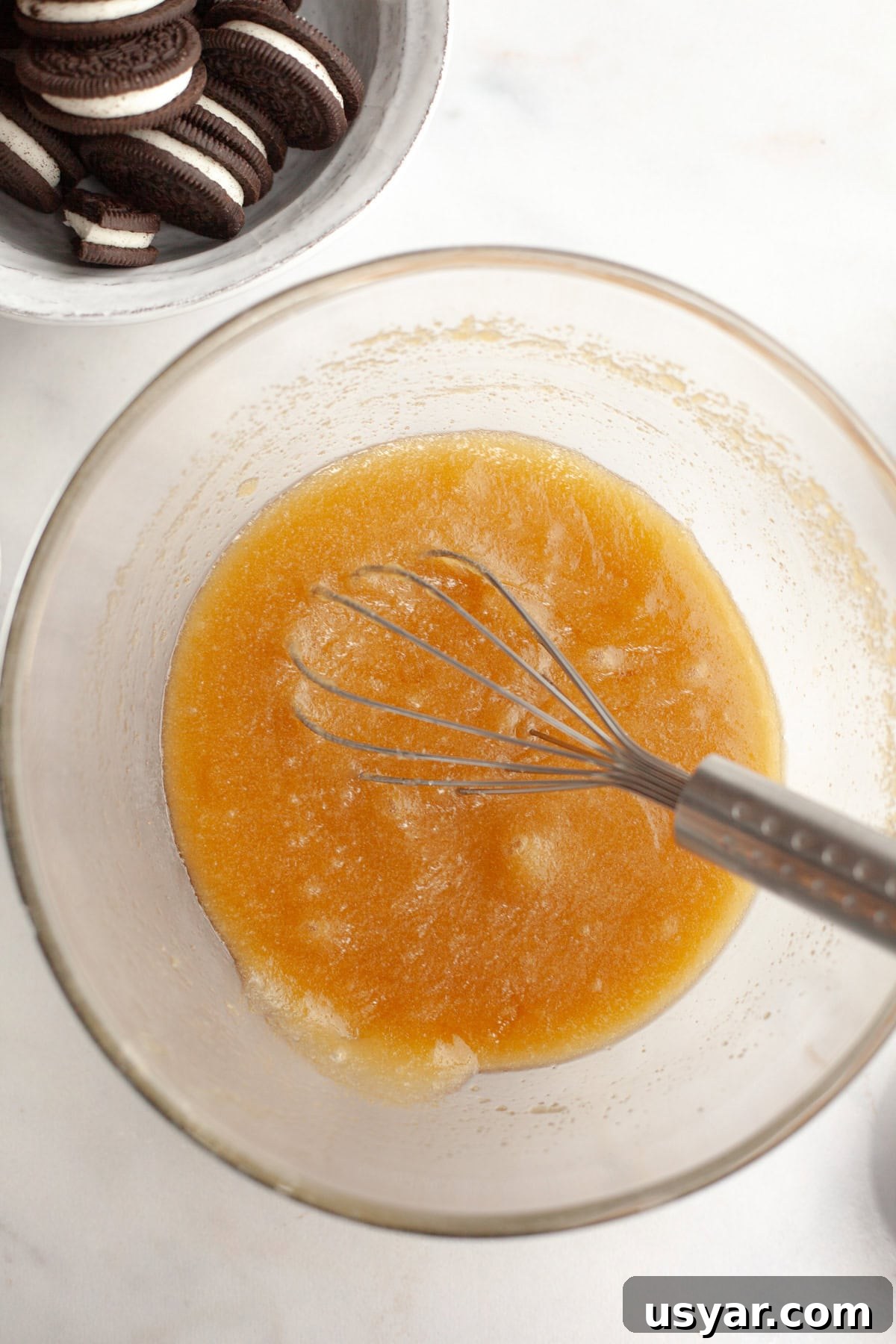 Melted butter and sugar in a glass bowl with a whisk.