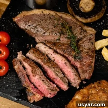 Rump steak cooked medium rare and served sliced on slate with mushroom, tomatoes, chips and onion loaf
