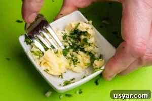 Mixing together Butter,chopped garlic and chopped fresh parsley in a small dish using a fork