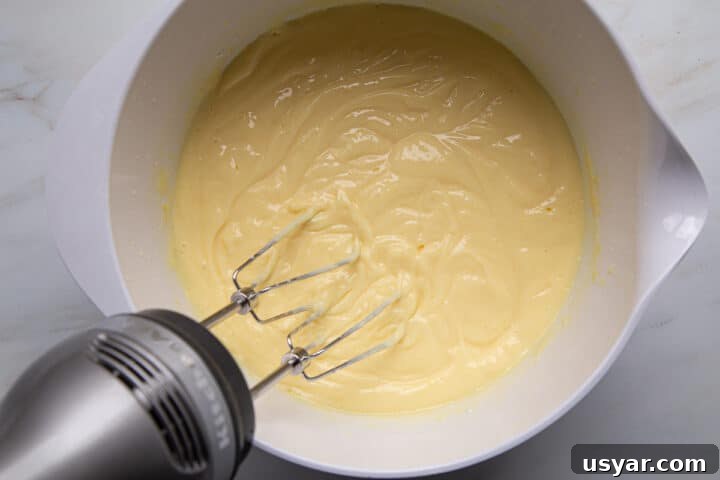 Creamy Banana Pudding Recipe with Sour Cream 5 vanilla pudding being mixed in a white mixing bowl with a hand mixer.