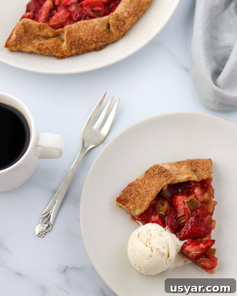 Rustic Strawberry Rhubarb Galette with Rye Crust 2 A slice of strawberry rhubarb galette with ice cream and a fork and a cup of coffee
