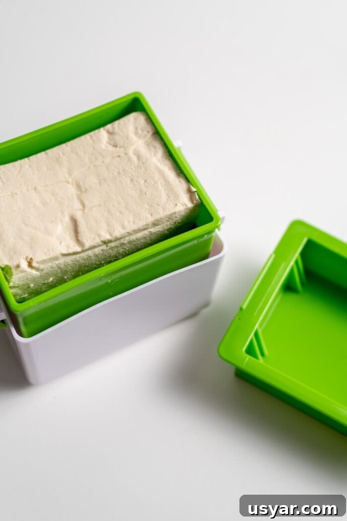 A block of tofu in a tofu press.