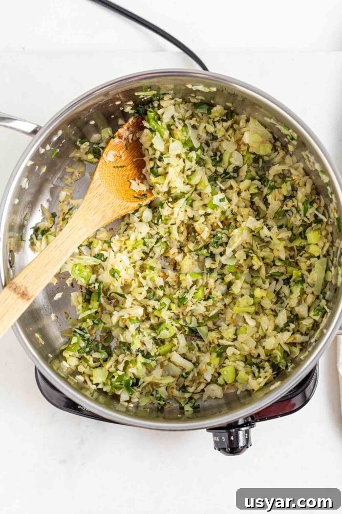 Sautéed cabbage, onion and cilantro in a skillet on a cooktop.