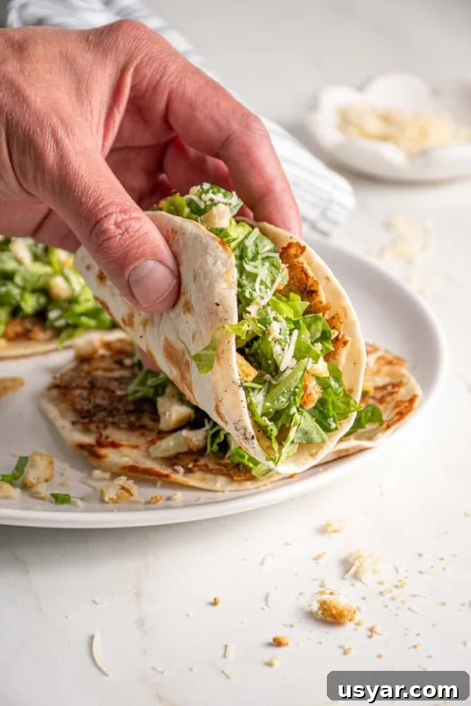 A hand holding a chicken caesar smash taco.