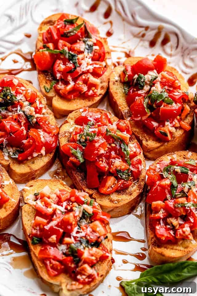 Bruschetta served on a white platter. white platter with toasted bread sliced covered in tomato salad with balsamic glaze