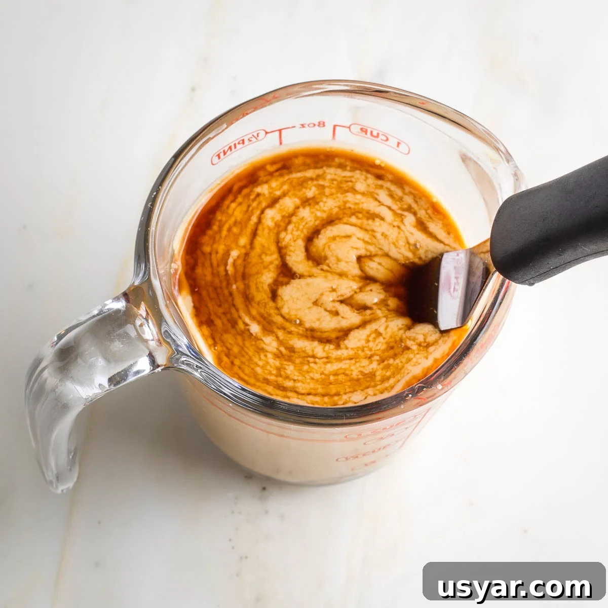 Crispy Sesame Seed Cookies Recipe 5 Swirl of maple syrup being mixed into a cup of tahini.