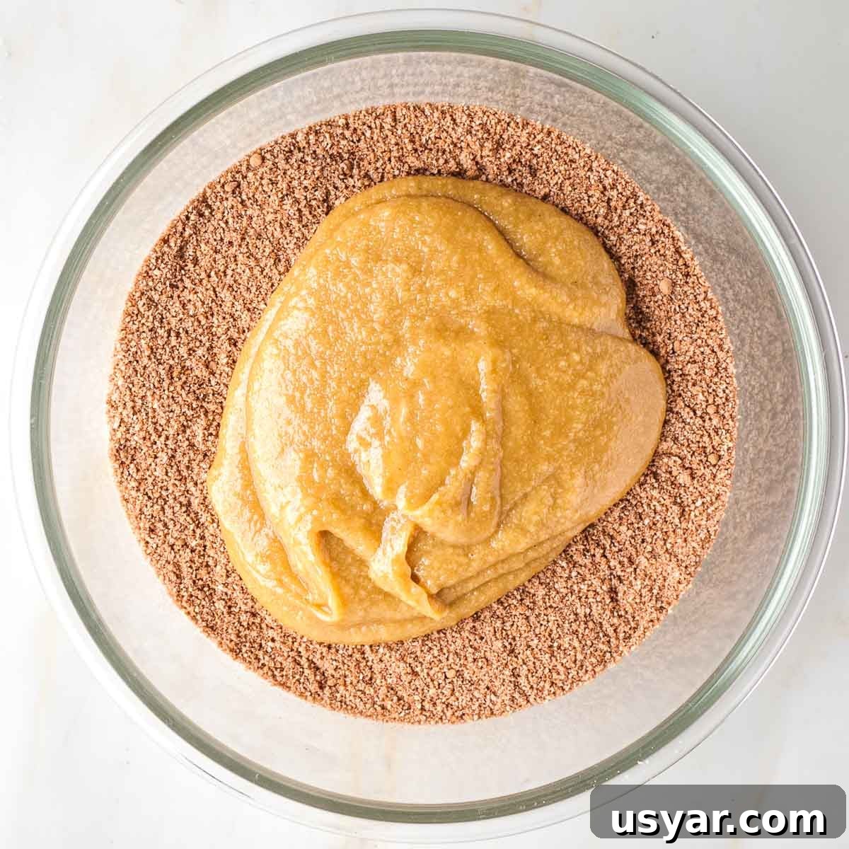 Crispy Sesame Seed Cookies Recipe 7 Dark brown powdery ingredients on the bottom of a glass bowl, topped with a caramel colored liquid.