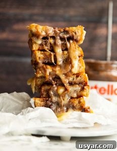 Nutella Grilled Cheese 4 nutella sandwich halves stacked on each other with jar of nutella blurred in background