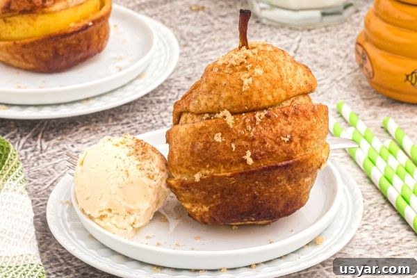 Crispy Honey-Glazed Pears in the Air Fryer 2 Golden pear wrapped in a layer of puff pastry strips. Served on a white plate with vanilla ice cream.