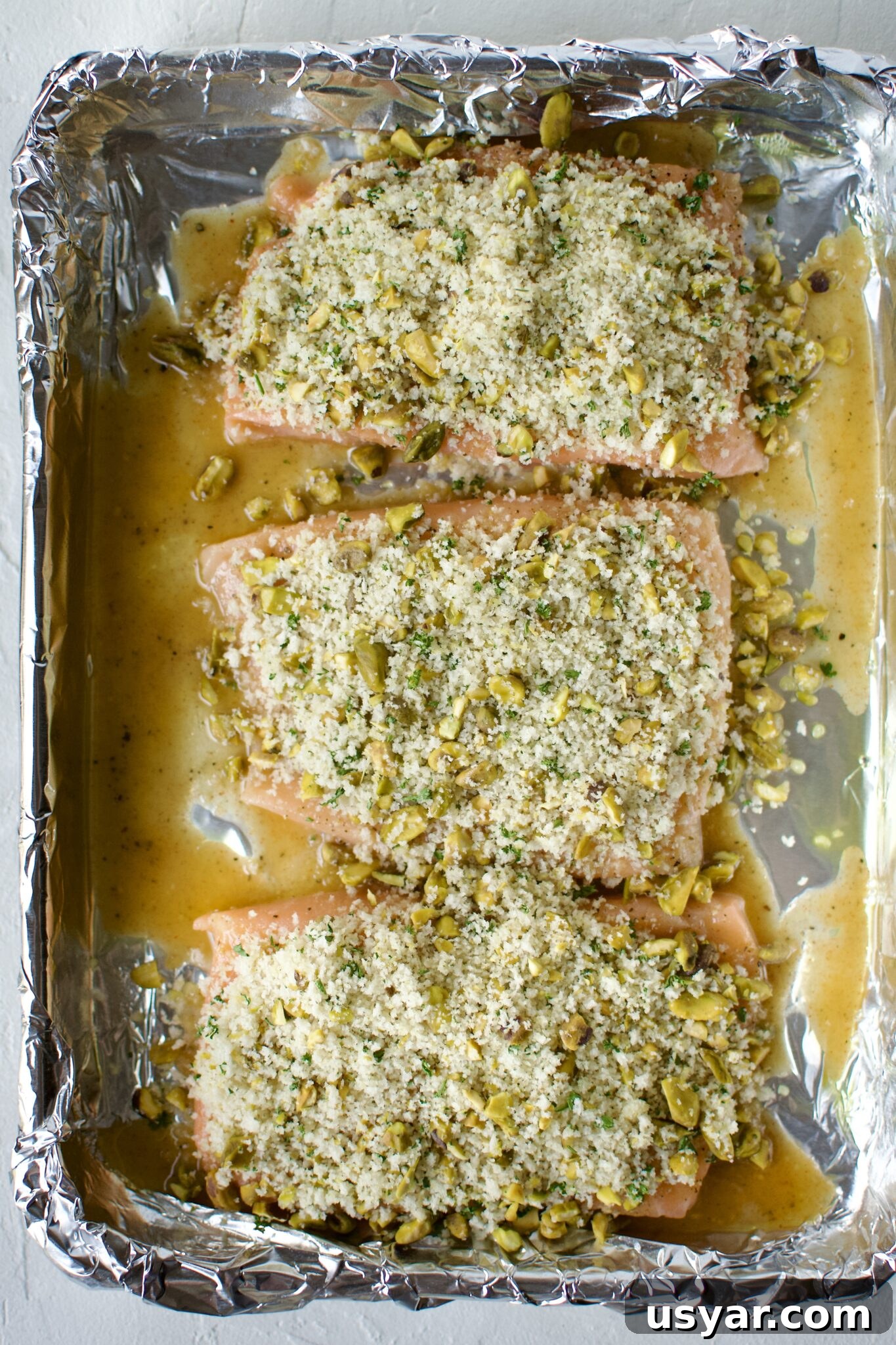Salmon fillets topped with the pistachio crust ready to be baked.
