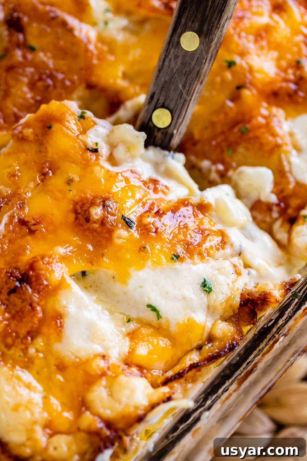 scalloped potatoes with cheese being lifted out of the pan with a spatula