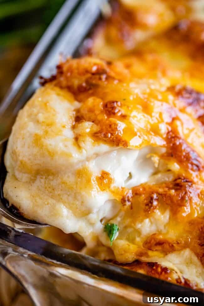 scalloped potatoes recipe with cheese topping being lifted out of the pan with a spoon
