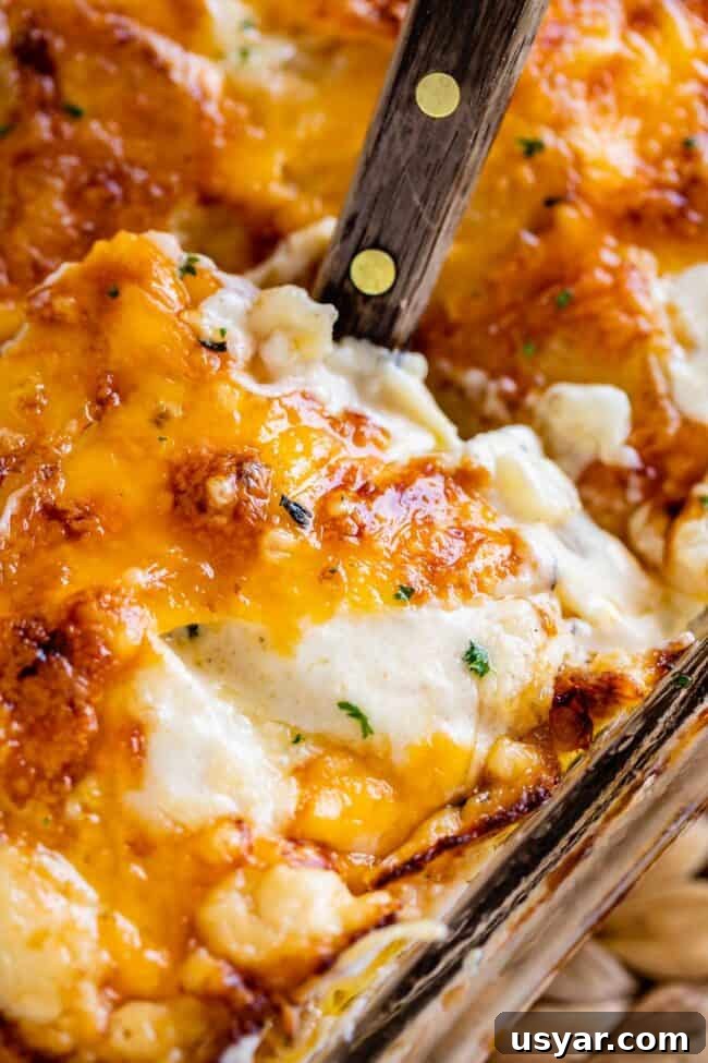 scalloped potatoes with cheese being lifted out of the pan with a spatula