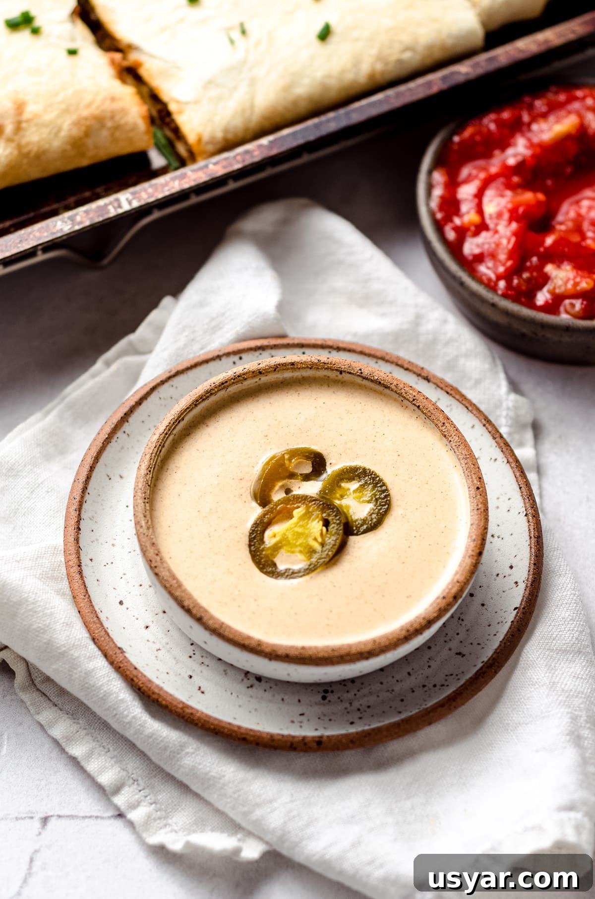 A bowl of quesadilla sauce topped with jalapeño rings.