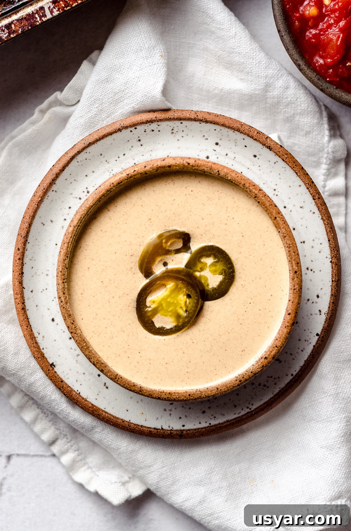 A bowl of quesadilla sauce topped with jalapeño rings.