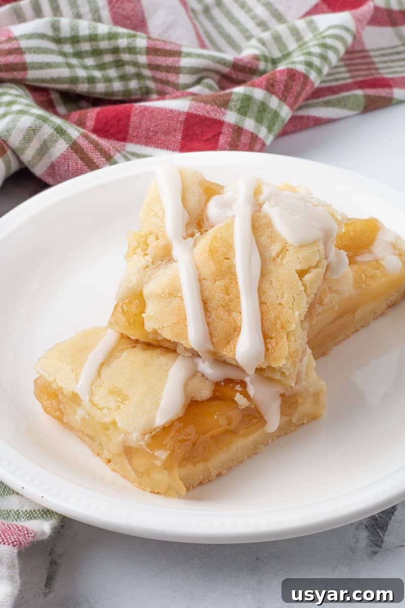 Cinnamon-Apple Pie Bars with Vanilla Glaze 2 Three apple pie bars on white plate.
