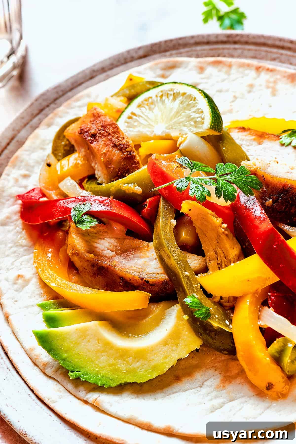These perfectly-seasoned Crockpot Chicken Fajitas are easy to make, perfect for busy days when you want a home-cooked meal without the hassle! Close-up shot of tortillas with fajita chicken.
