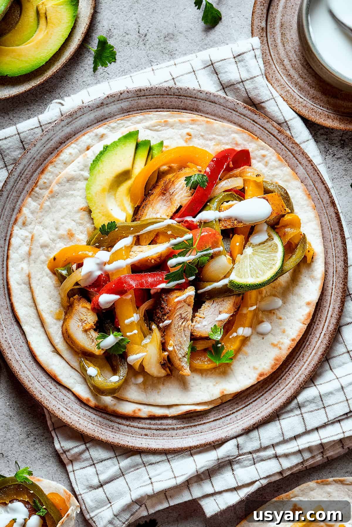 These perfectly-seasoned Crockpot Chicken Fajitas are easy to make, perfect for busy days when you want a home-cooked meal without the hassle! Crockpot chicken fajitas plated and topped with lime, avocado, and sour cream.