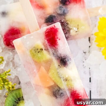 two popsicles with fruit on crushed ice
