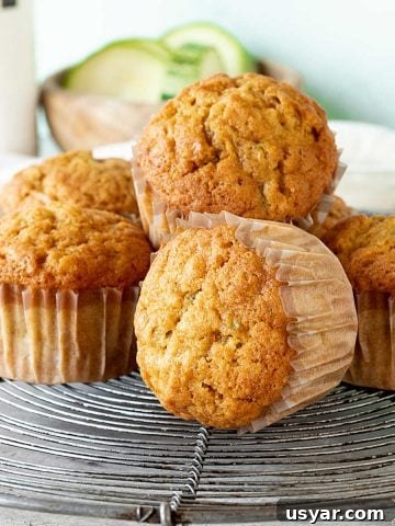 Stacked pumpkin zucchini muffins in paper liners on a wire rack.