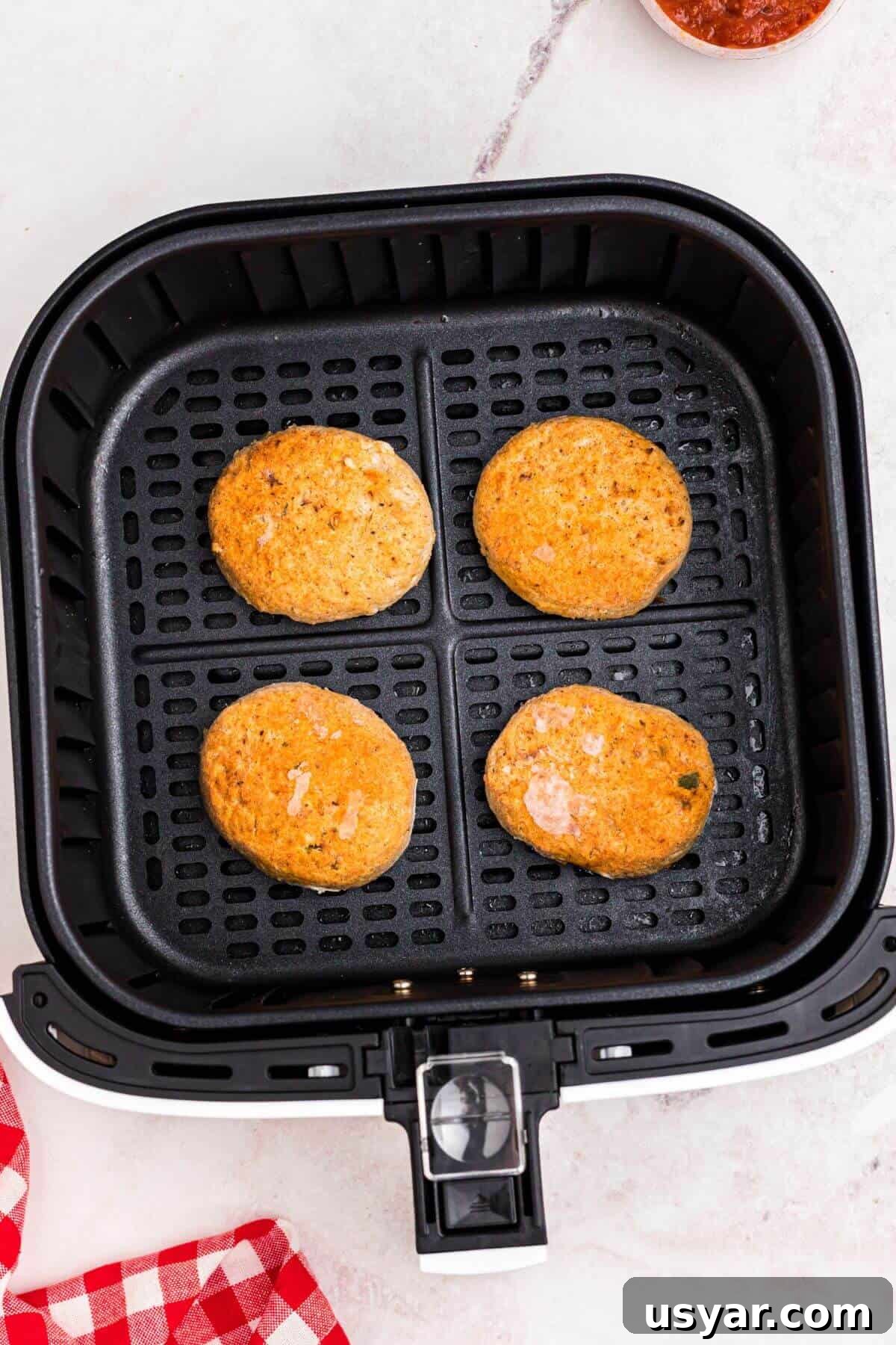 Frozen golden crab cakes in the air fryer basket before being air fried. 