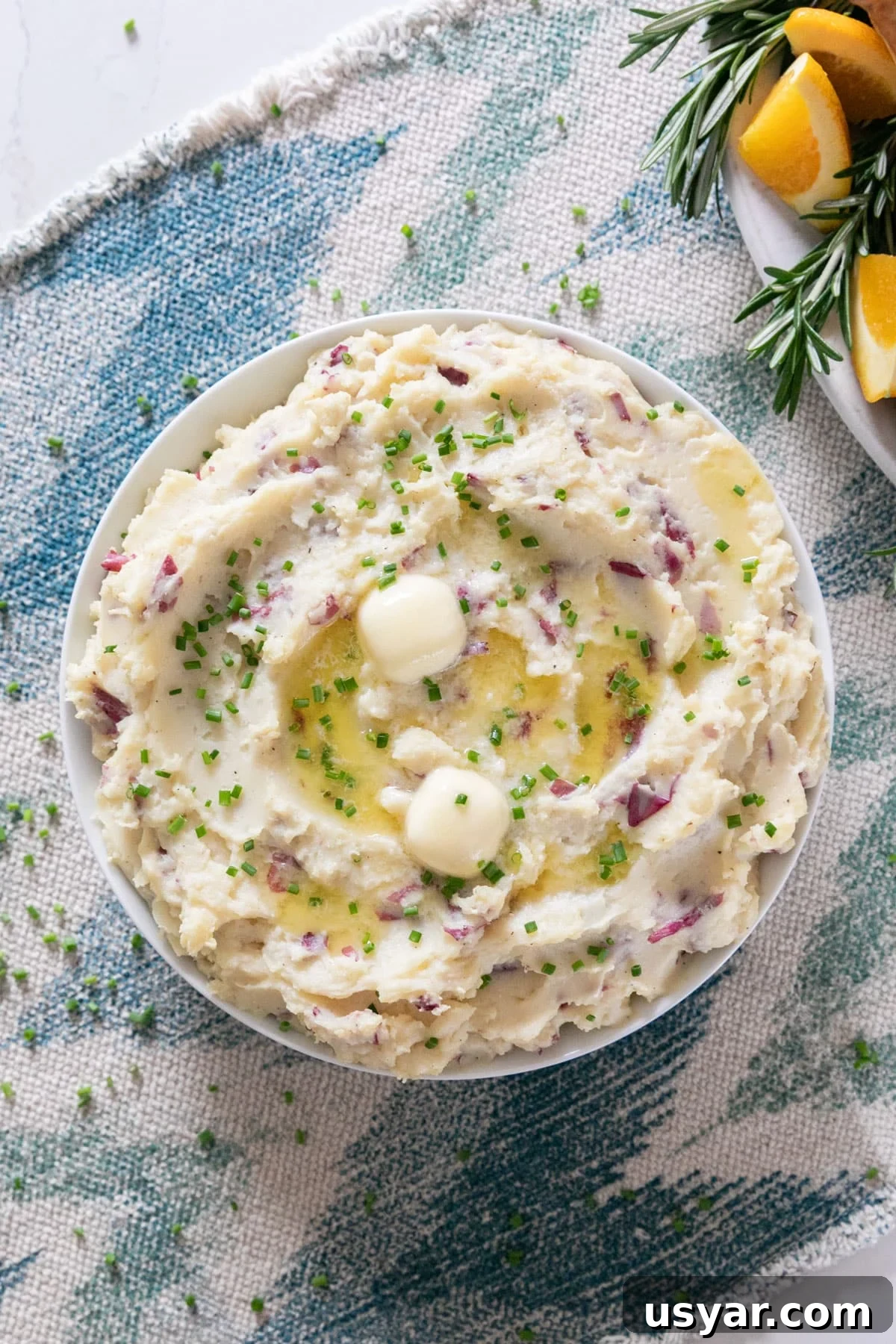 Creamy Gouda Mashed Potatoes 2 An overhead image of mashed potatoes with melting butter and chives on top.
