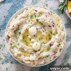 An overhead image of mashed potatoes with melting butter and chives on top.