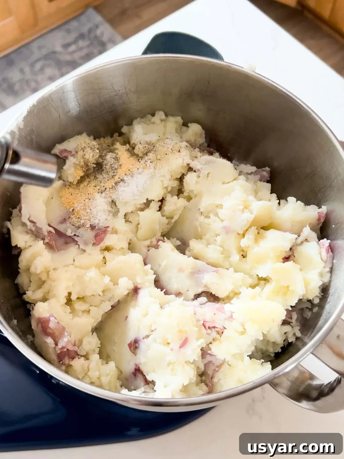 Creamy Gouda Mashed Potatoes 7 Partially mashed potatoes in stand mixer bowl with other ingredients ready to finish being mashed.