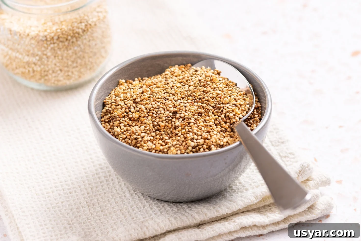 An image of puffed quinoa in a small bowl with a spoon resting on top.