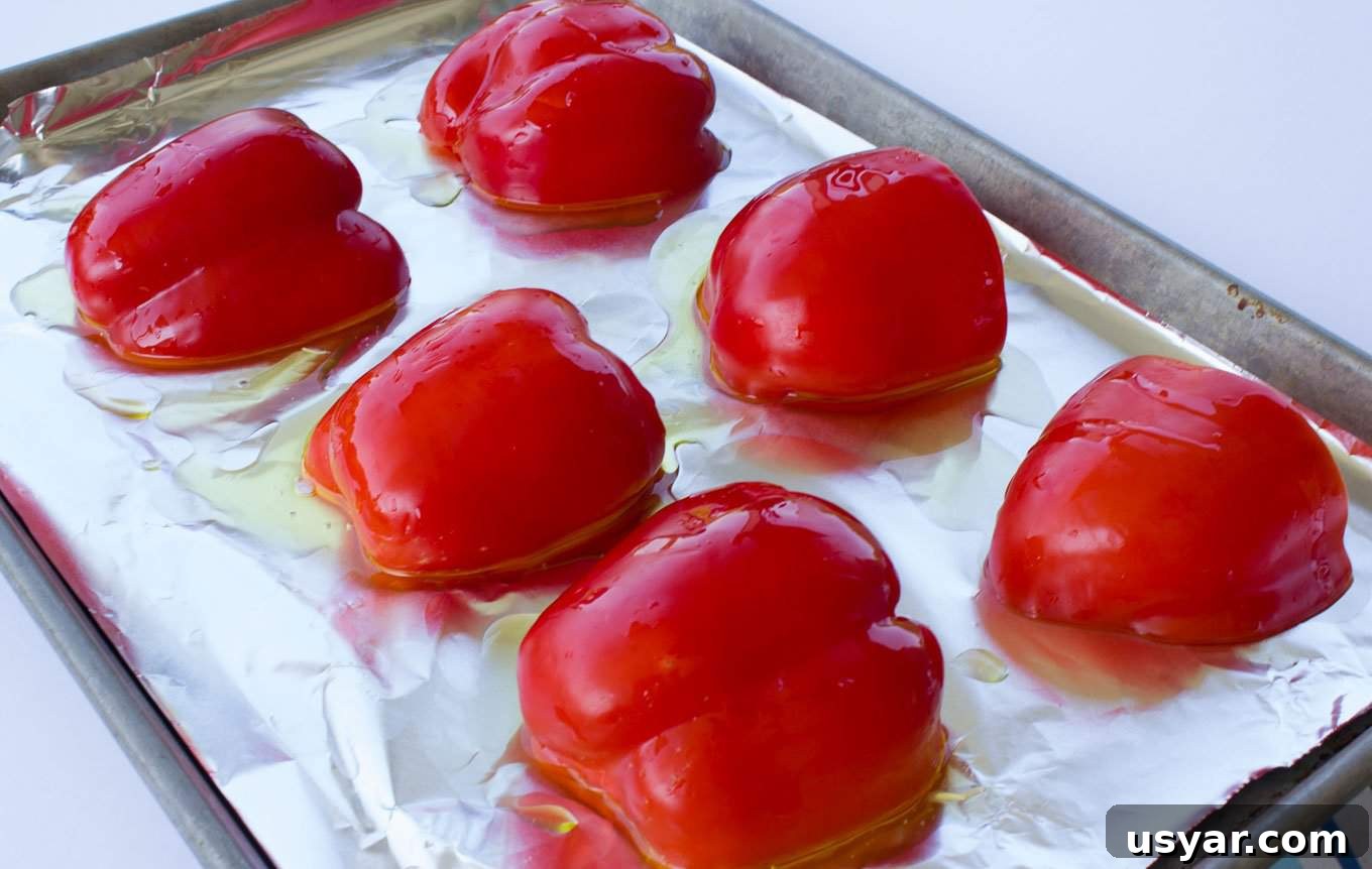 How to Roast Red Peppers at Home 3 Six raw red pepper halves cut side down on a cookie sheet with olive oil