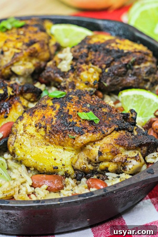 Oven-Baked Jerk Chicken with Sticky Citrus Glaze 2 baked jerk chicken thighs with coconut rice and kidney beans n a cast iron skillet.