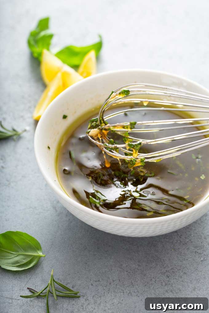 Tangy Balsamic Marinade for Chicken 3 Marinade with balsamic vinegar, fresh garlic and herbs in a white mixing bowl.