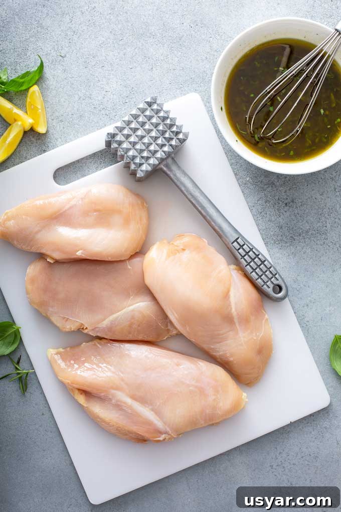 Tangy Balsamic Marinade for Chicken 8 Boneless chicken breast on a cutting board next to a meat mallet and a bowl of balsamic and herb marinade