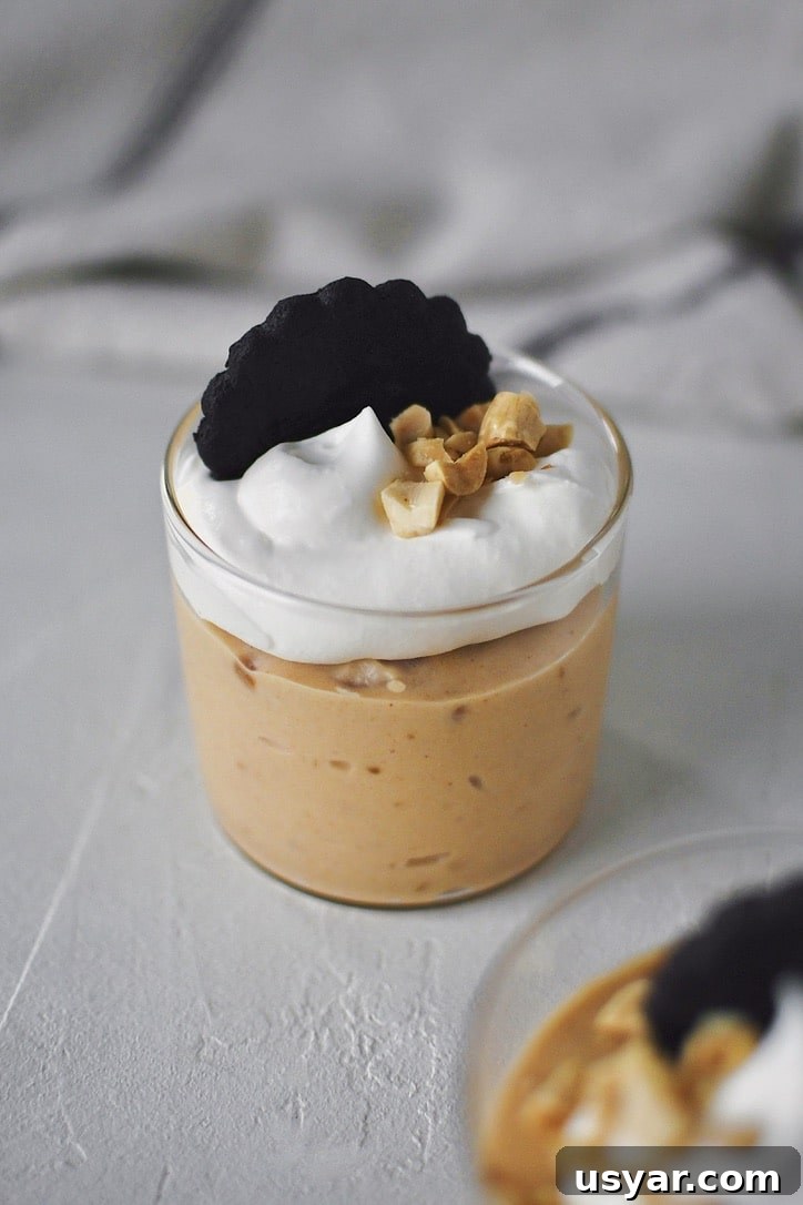 Decadent Peanut Butter Mousse Recipe 2 Peanut Butter Mousse in a small cup, topped with whipped cream, peanuts, and a chocolate wafer.
