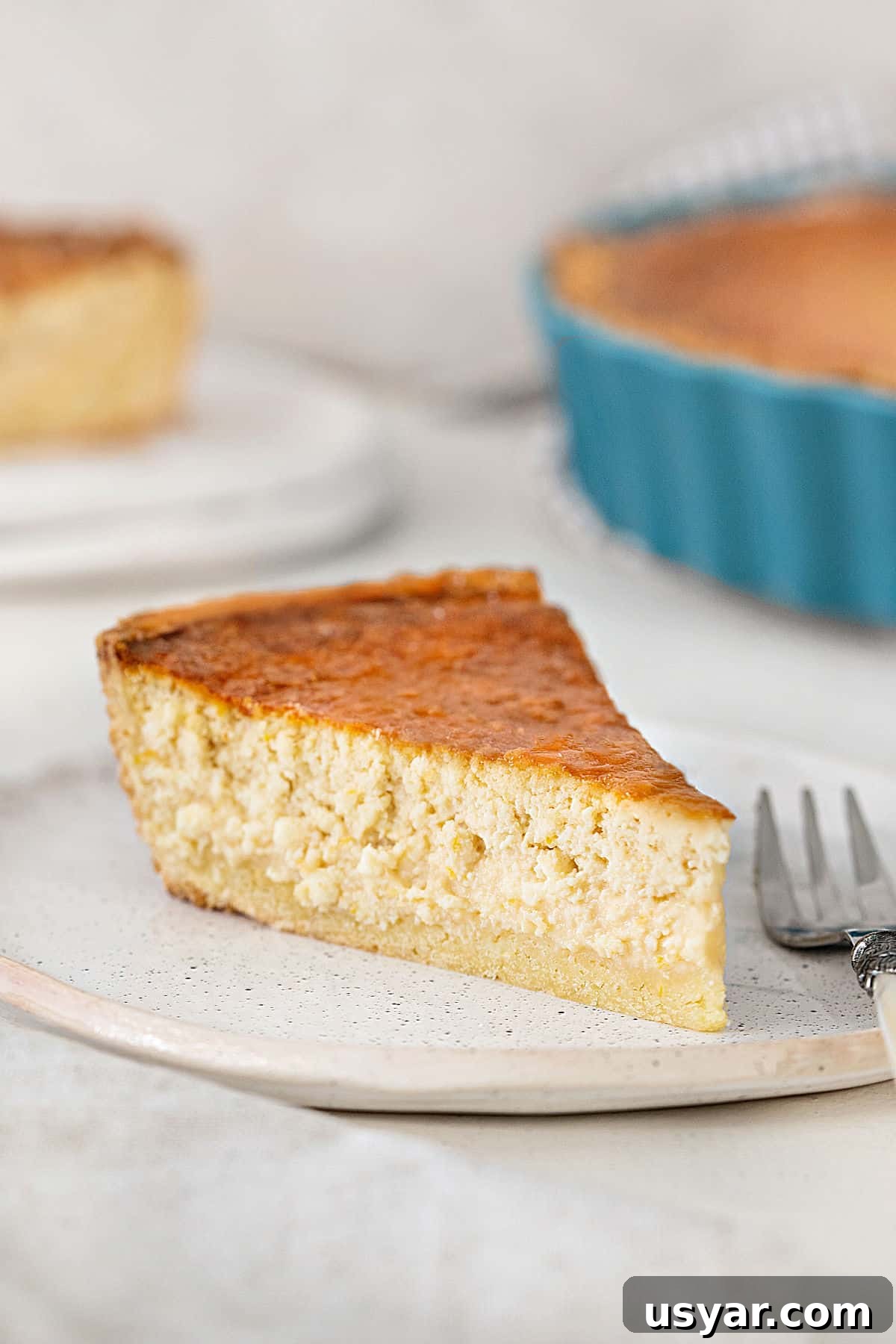 Classic Italian Ricotta Pie Recipe 2 Single slice of ricotta pie on a white plate. Teal pie dish in the white background.