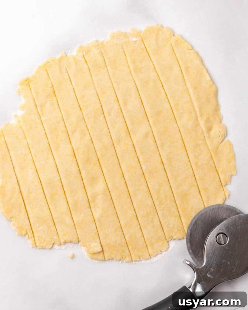Classic Italian Ricotta Pie Recipe 10 Strips cut on a rolled piece of pie dough on white marble. Pizza cutter.