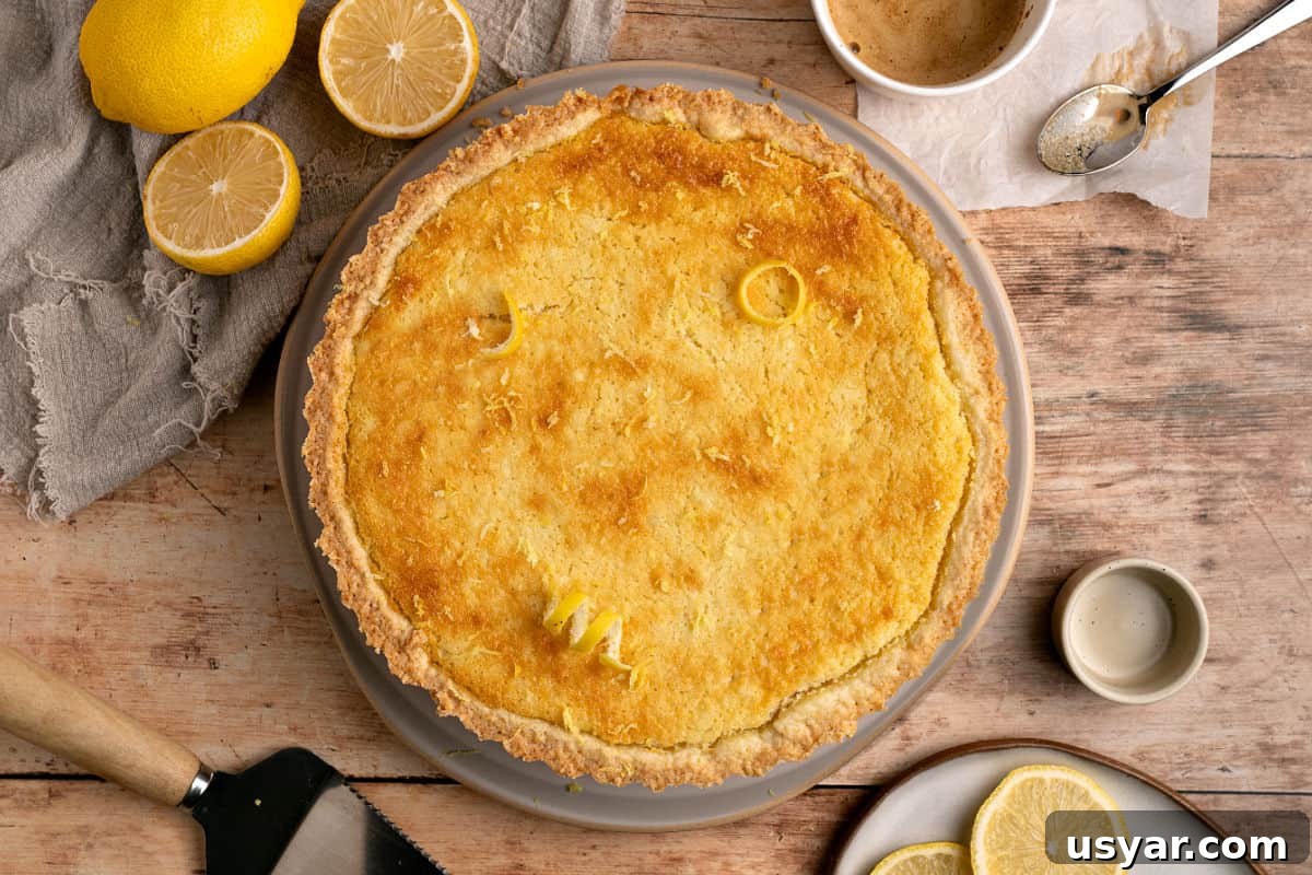 Classic Italian Ricotta Pie Recipe 3 Pie plate with ricotta pie, wooden table, lemons, gray towel.