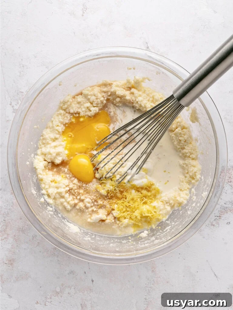 Classic Italian Ricotta Pie Recipe 6 Glass bowl with lemon ricotta pie filling ingredients. Metal whisk. Light gray background.