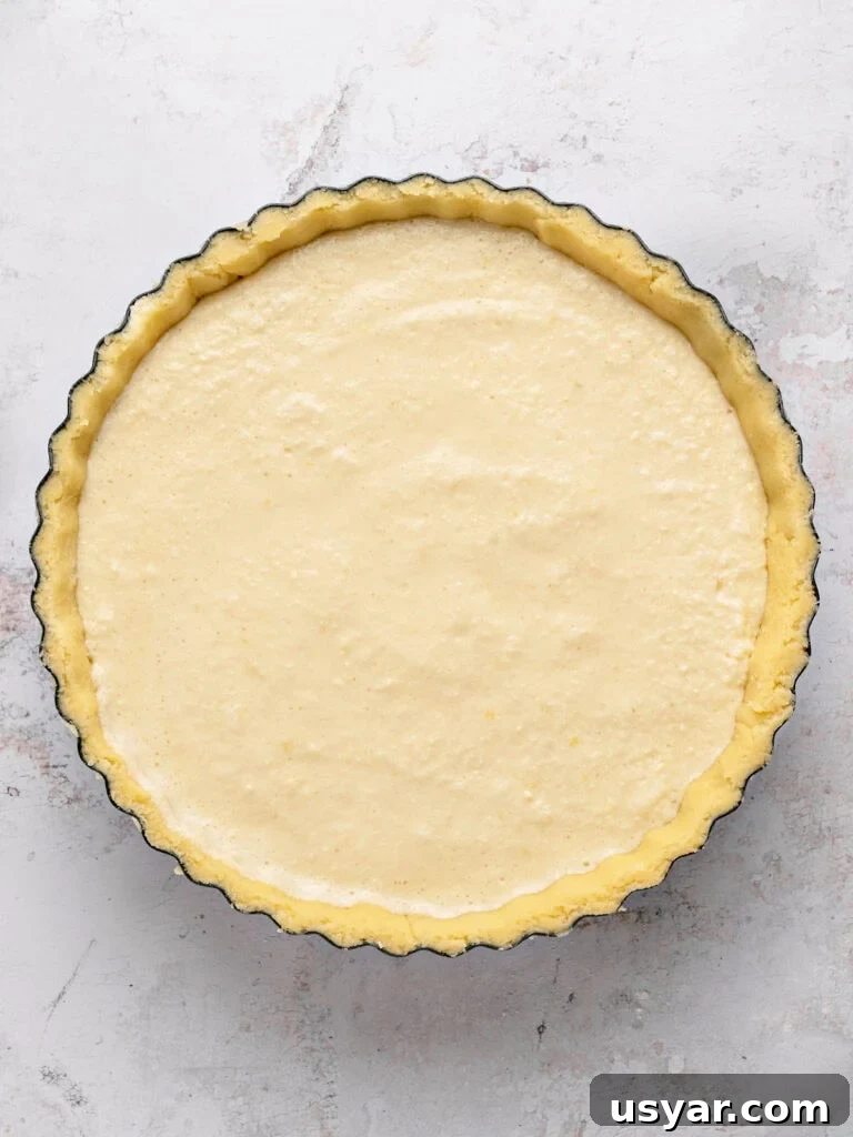 Classic Italian Ricotta Pie Recipe 8 Round pie pan with ricotta pie before baking. Light gray surface.