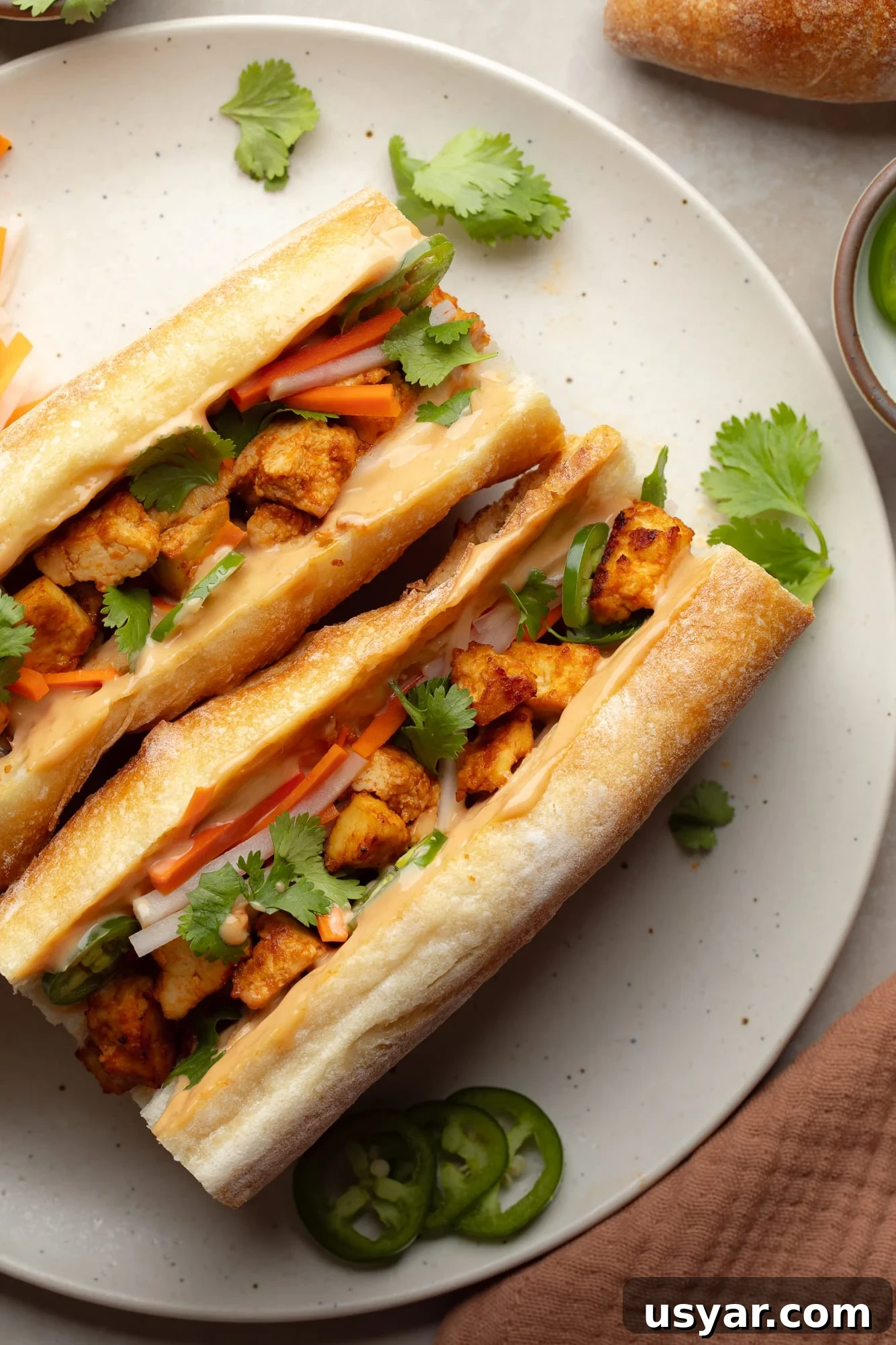 Vegan Banh Mi Sandwich with Pickled Vegetables 2 overhead view of two vegan banh mi sandwiches on a white plate.