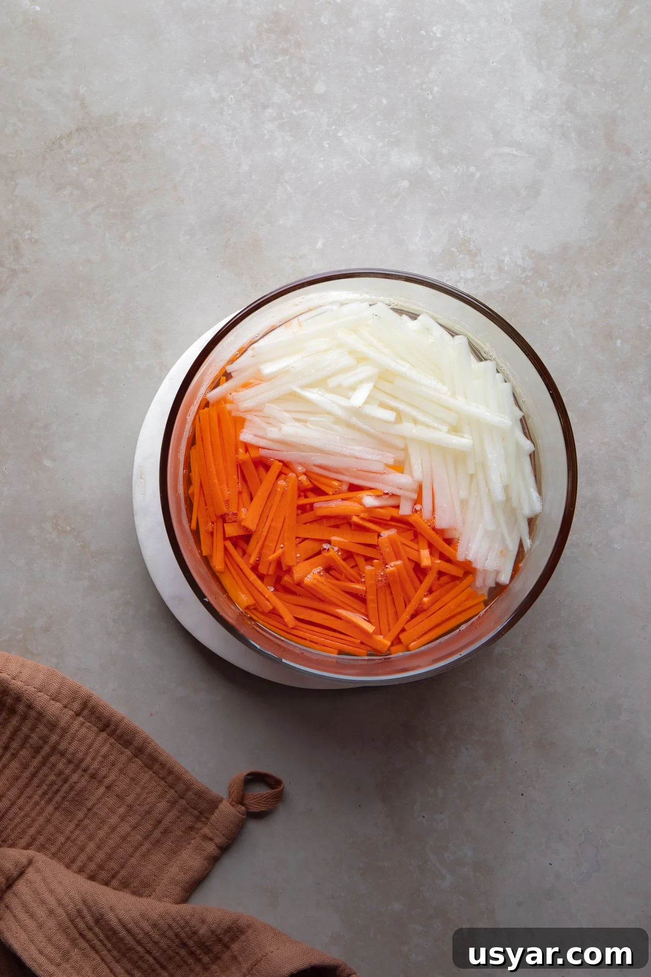 Vegan Banh Mi Sandwich with Pickled Vegetables 3 pickled carrot and daikon matchsticks in a glass container.