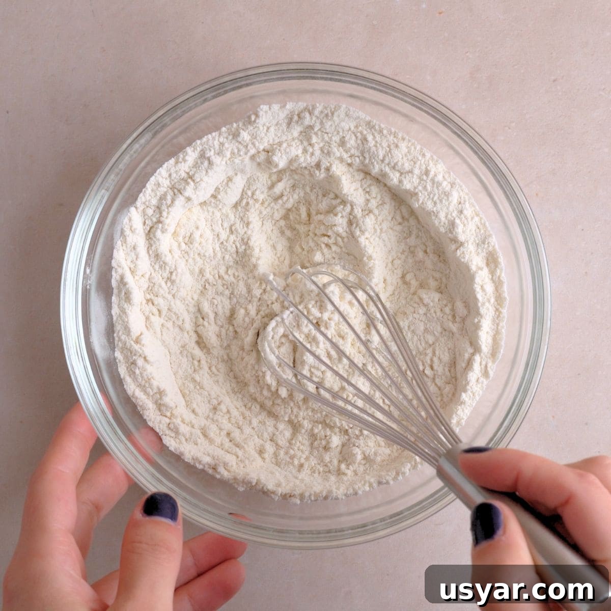 How to Make Chewy Salted Caramel Oatmeal Cookies 4 Flour, salt, baking soda, and baking powder being whisked together in a bowl.