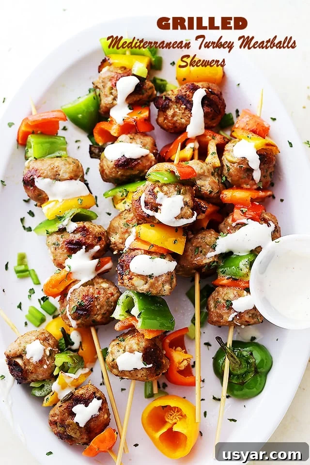 Juicy, flavor-packed turkey meatballs made with feta, olives, and herbs, grilled to perfection and served on skewers with bell peppers. Turkey meatballs and bell pepper slices on skewers, and drizzled with homemade garlic yogurt sauce.