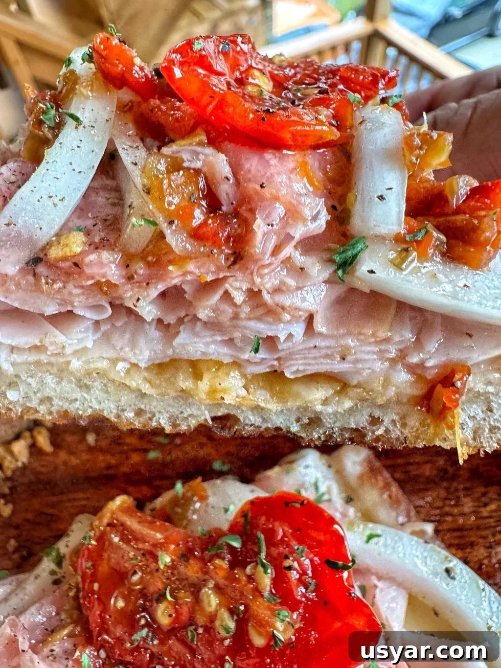 Open-Faced Italian Subs Recipe with Melty Mozzarella 7 A close up shot of an open faced sub sandwich with peppers, onions, and shaved deli meat.